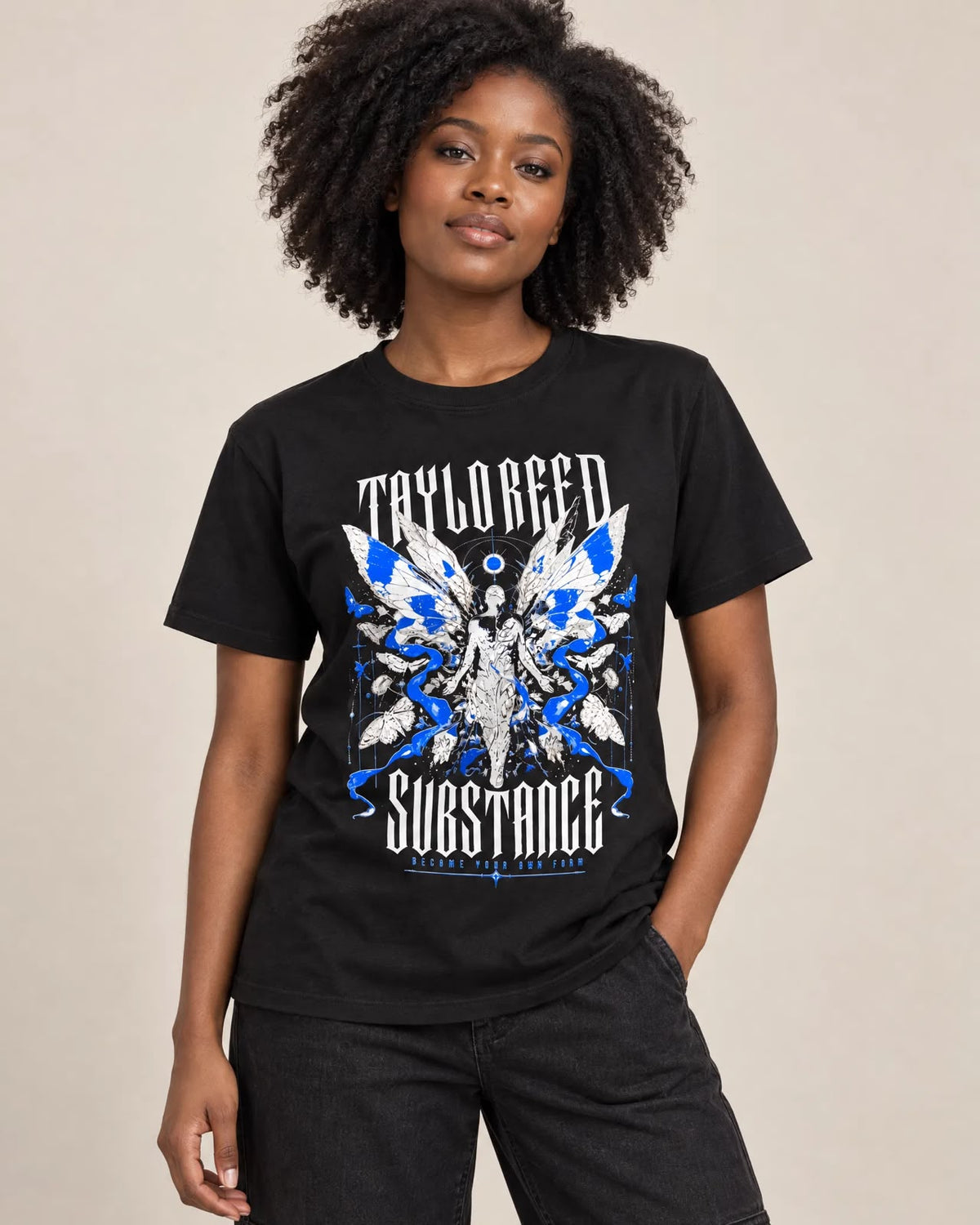 Model wearing the black Become Your Own Form graphic T-shirt, showing blue-and-white wing artwork on the front.