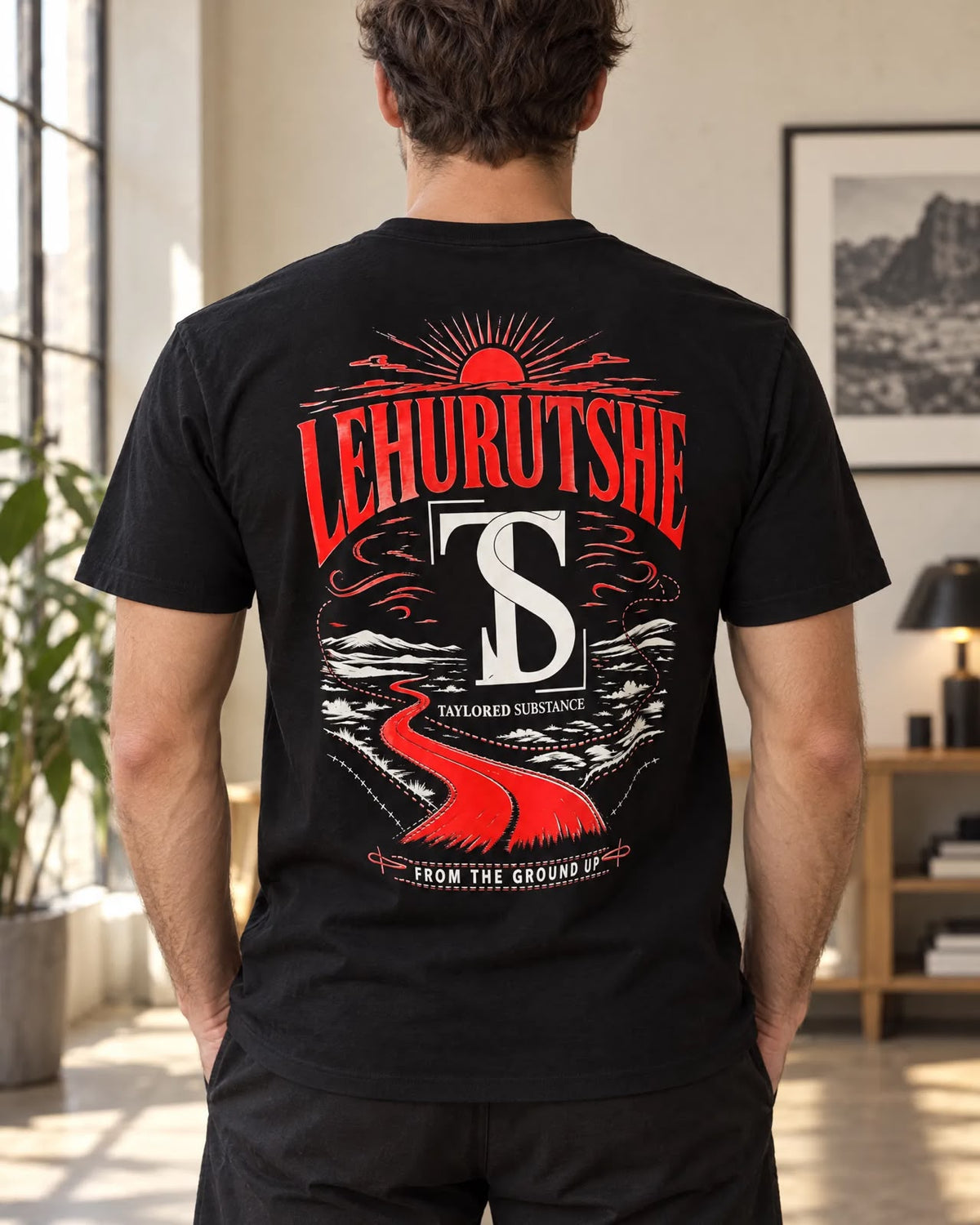 Back view of a model wearing the Rewire Yourself tee with a red-and-white landscape graphic.