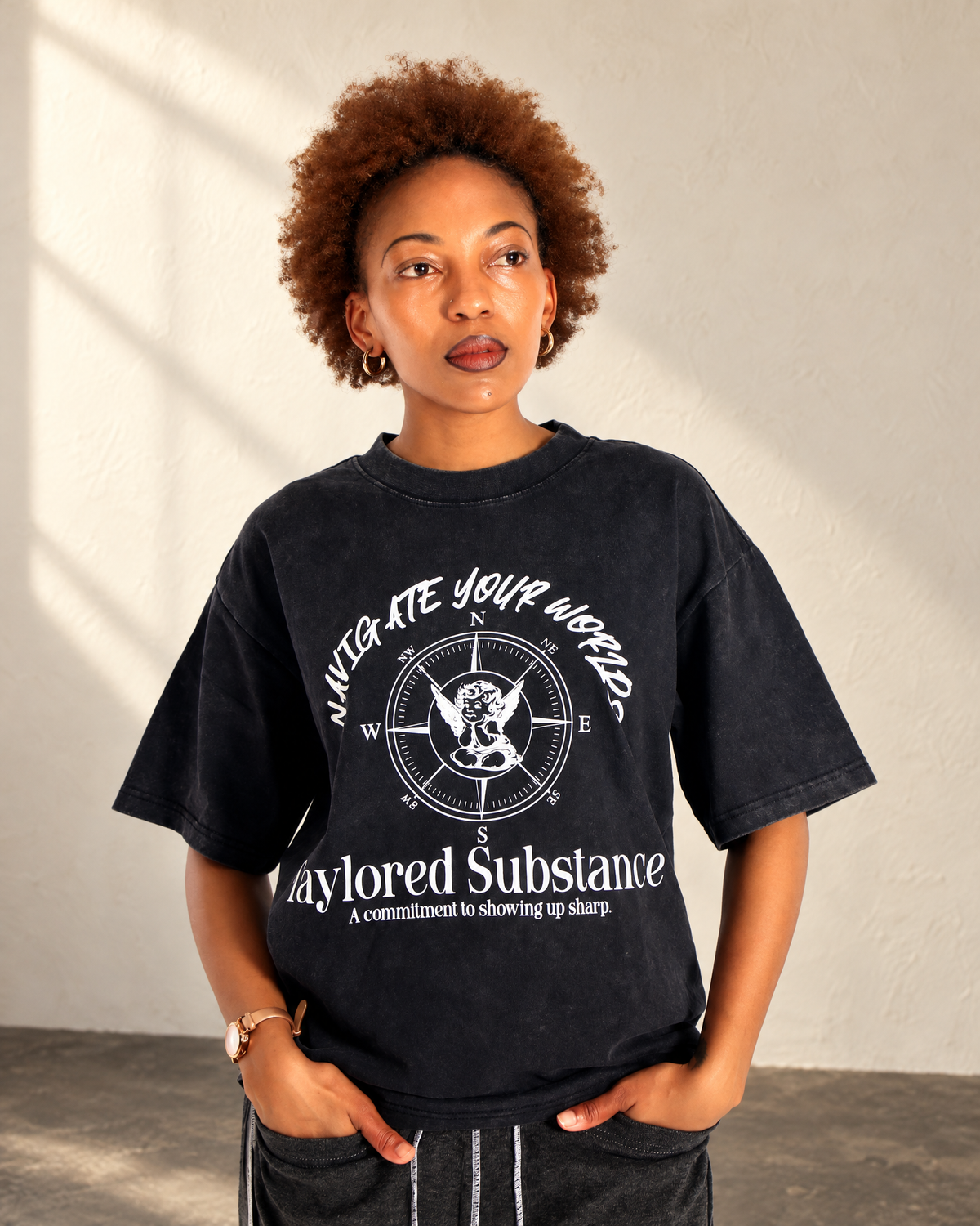 Close front view of the dark stone-washed tee showing its white compass and Navigate Your Worlds graphic.