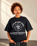 Model wearing the dark stone-washed T-shirt with white Navigate Your Worlds lettering and compass artwork on the front.